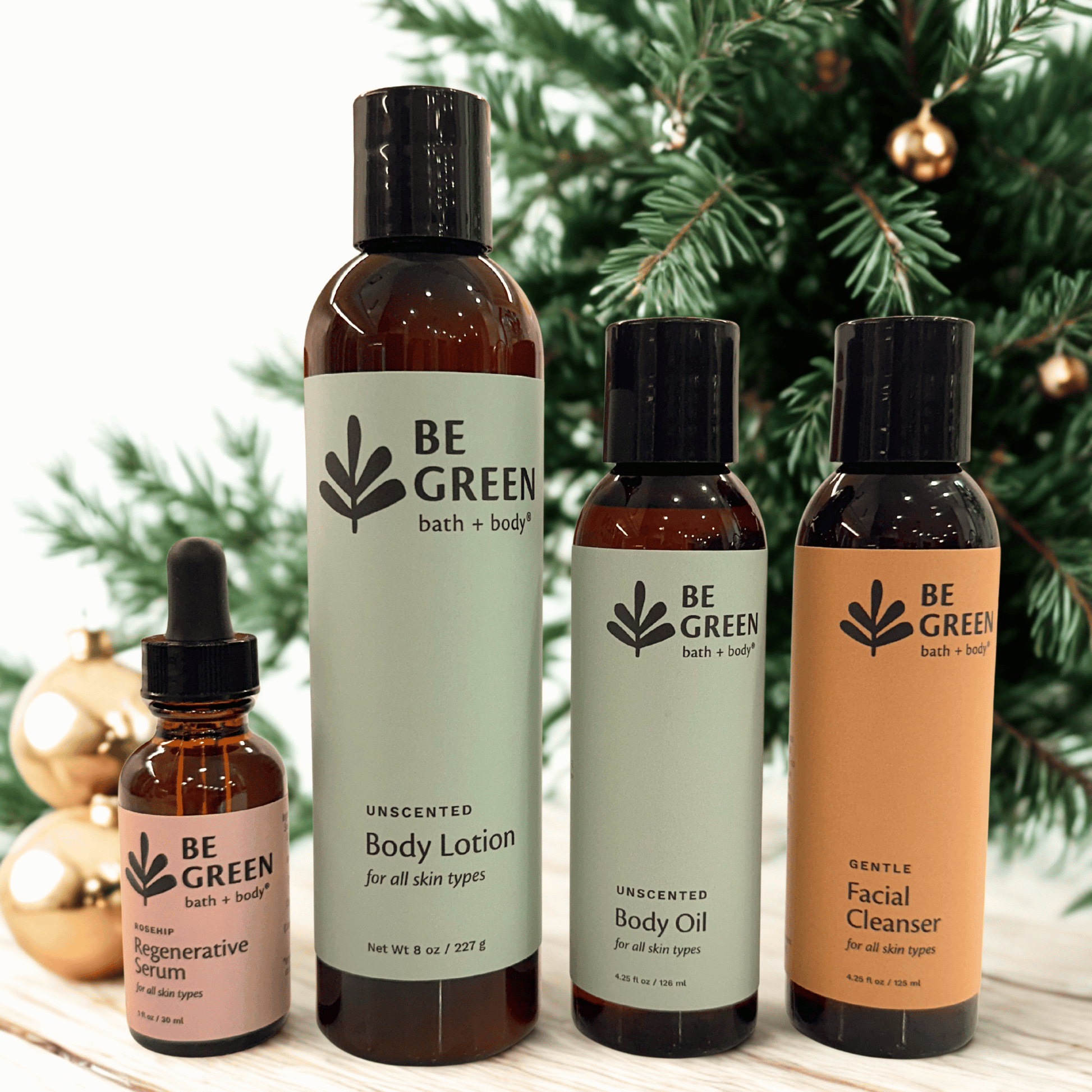 Collection of 'Be Green' bath and body products with a Christmas tree in the background