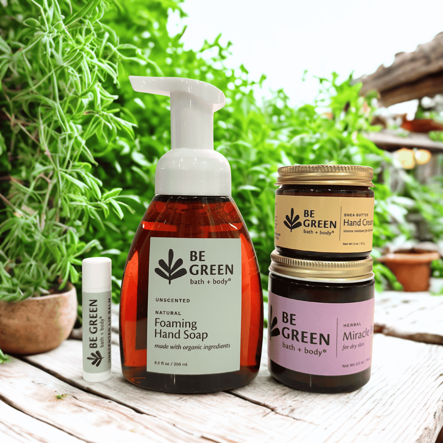 Collection of 'Be Green' bath and body products on a wooden surface with greenery in the background.