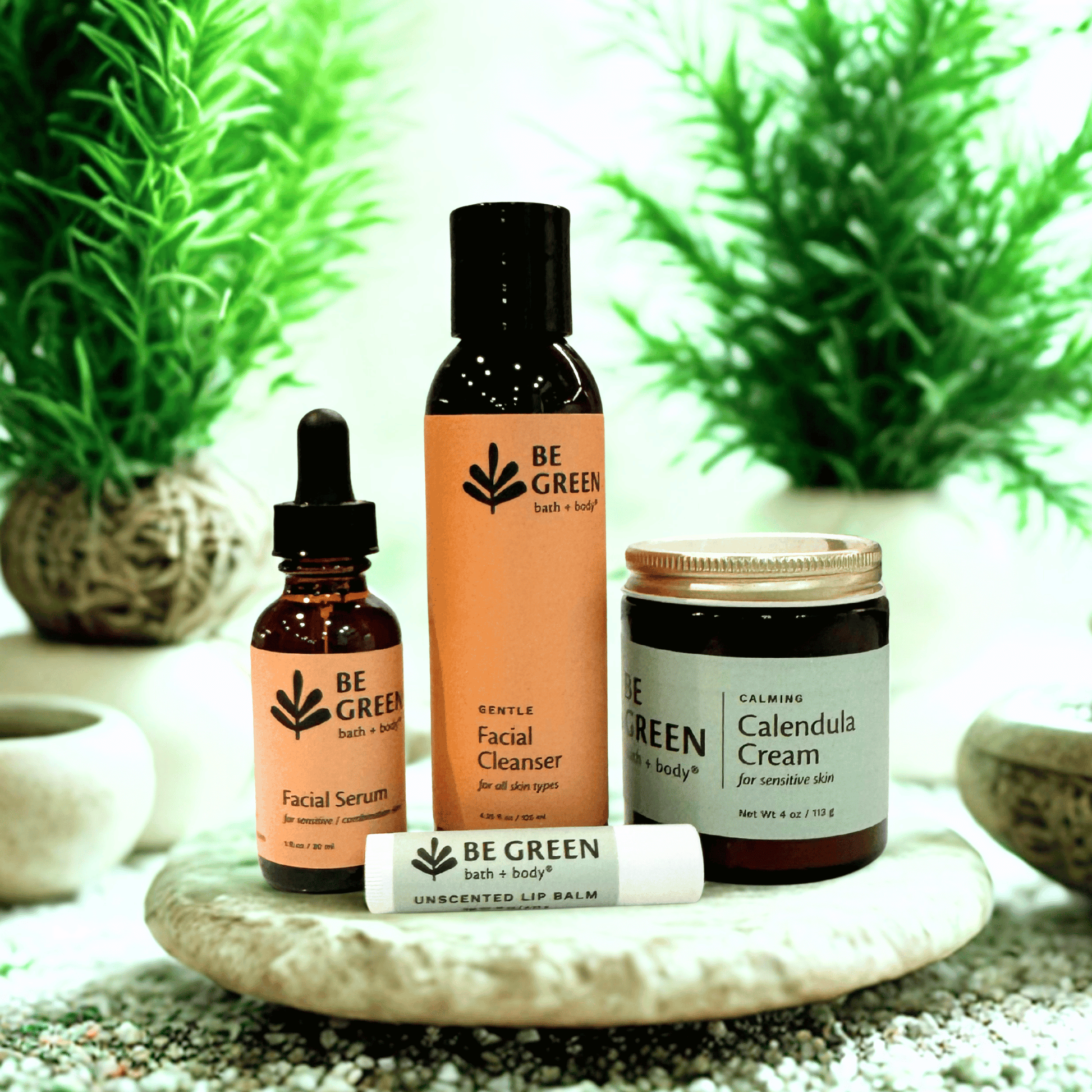Set of 'Be Green' skincare products on a stone surface with plants in the background
