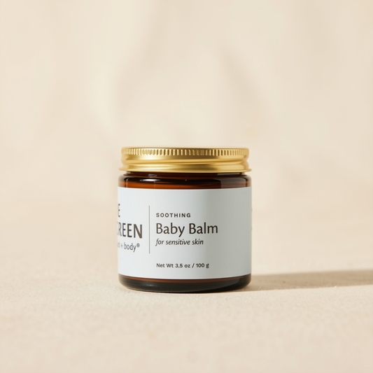 A small amber glass jar of baby balm with a gold metal lid and a white label reading 'Soothing Baby Balm for sensitive skin.' The jar is centered on a warm beige background.