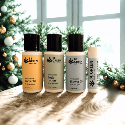 Four 'Be Green' skincare products on a wooden surface with a Christmas tree in the background.