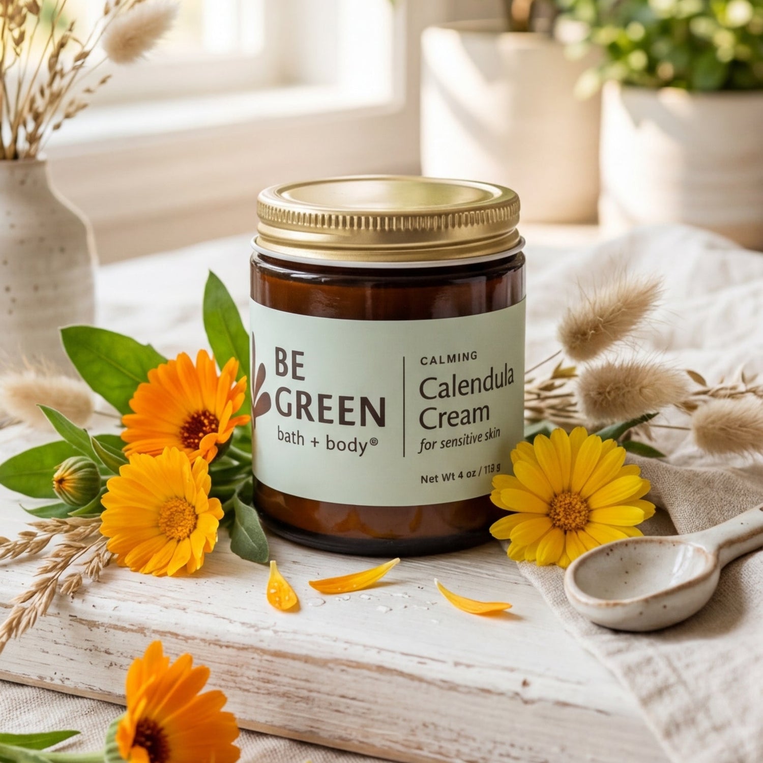 Jar of 'Be Green' calendula cream on a wooden surface with flowers and plants in the background