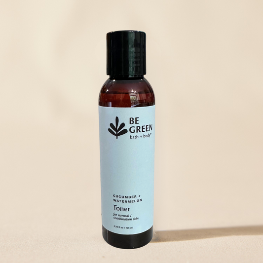 A bottle of BE GREEN Cucumber + Watermelon Toner with a light blue label and black cap, set against a solid beige background.