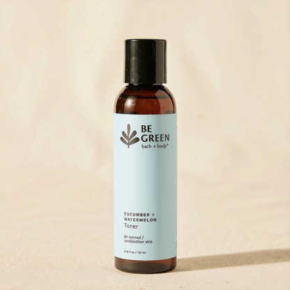 A bottle of BE GREEN Cucumber + Watermelon Toner with a light blue label and black cap, standing on a beige textured surface.