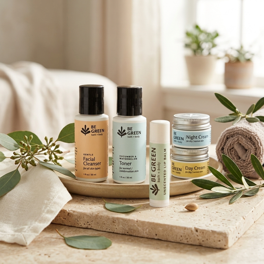 A skincare set from BE GREEN Beauty arranged on a stone tray with eucalyptus leaves and a rolled towel. The set includes Facial Cleanser, Toner, Lip Balm, and Night/Day Cream jars in soft neutral tones.
