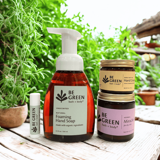 Collection of 'Be Green' bath and body products on a wooden surface with greenery in the background.