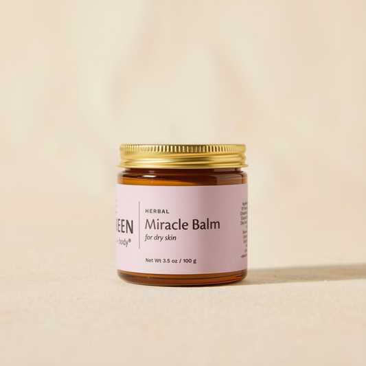 A small amber glass jar of Herbal Miracle Balm with a gold metal lid and a light pink label, set against a warm beige background.