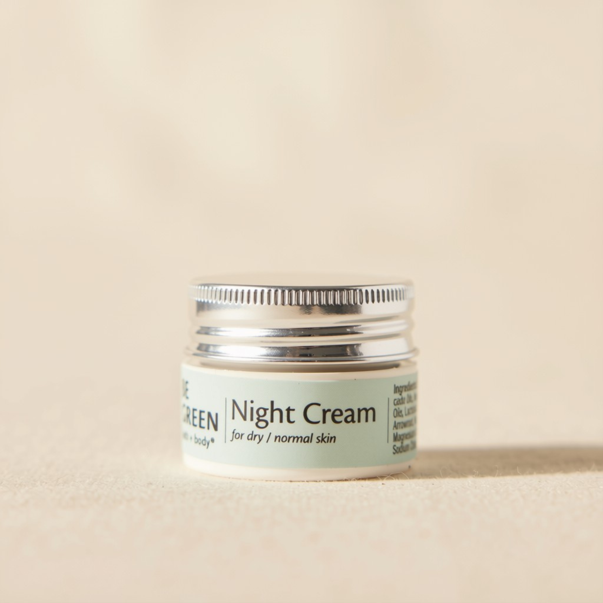 A trial size jar of Be Green Night Cream for dry skin with a silver metal lid and a pale green label, set against a warm beige background.