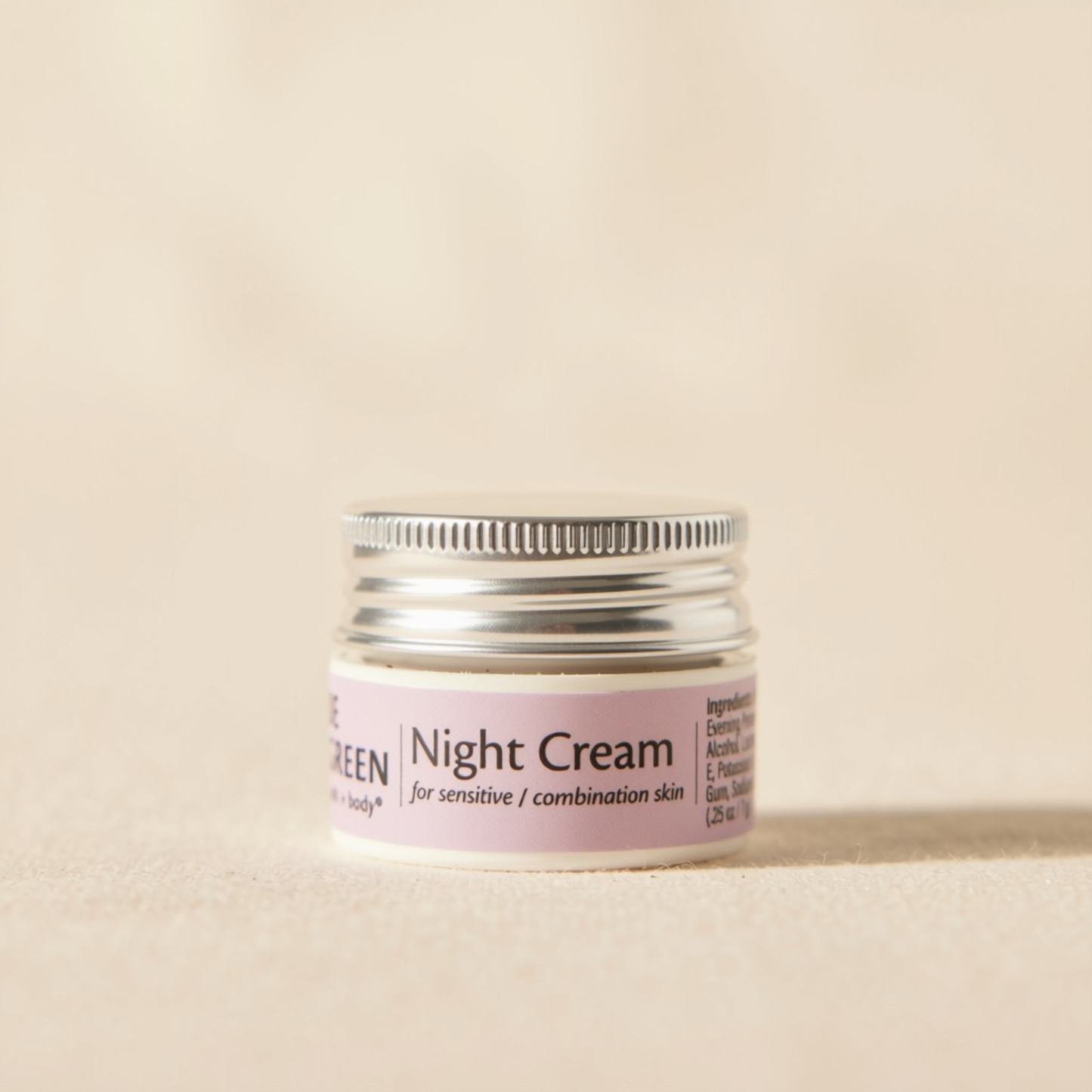 A trial size jar of Night Cream for sensitive skin with a silver metal lid and a light pink label, set against a warm beige background.
