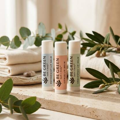 Three Be Green lip balms on a light stone surrounded by towels
